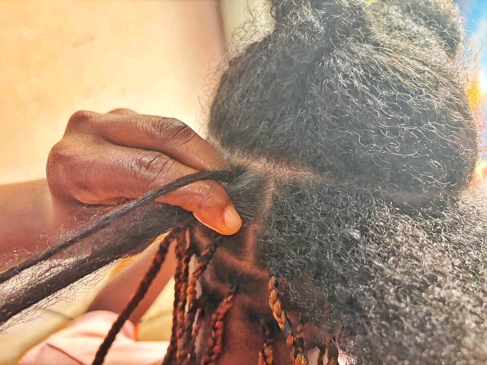 Close-up of hands braiding natural hair with extensions