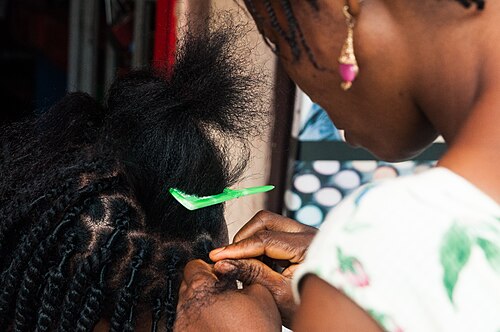 A braider working on a client's hair in the salon